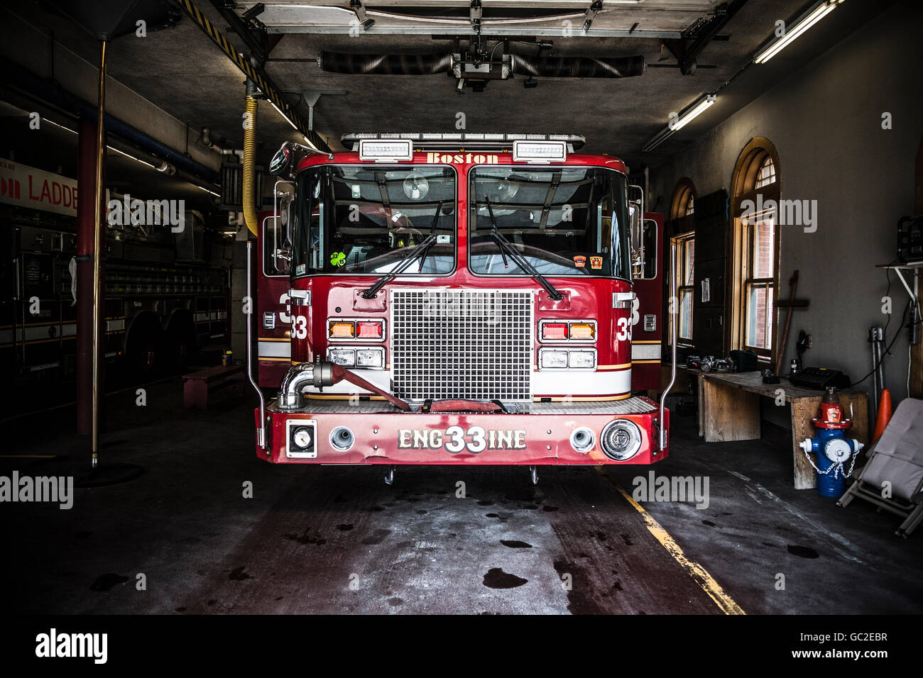 A fire truck is parked in the bay with all of the fire fighting equipment and gear ready to go. Boston Stock Photo