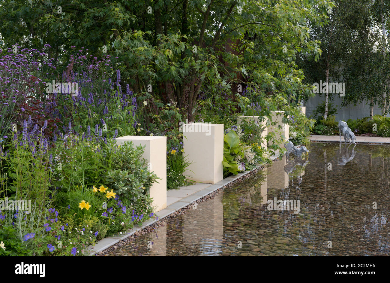 A large water feature, herbaceous borders and dog sculptures in the
