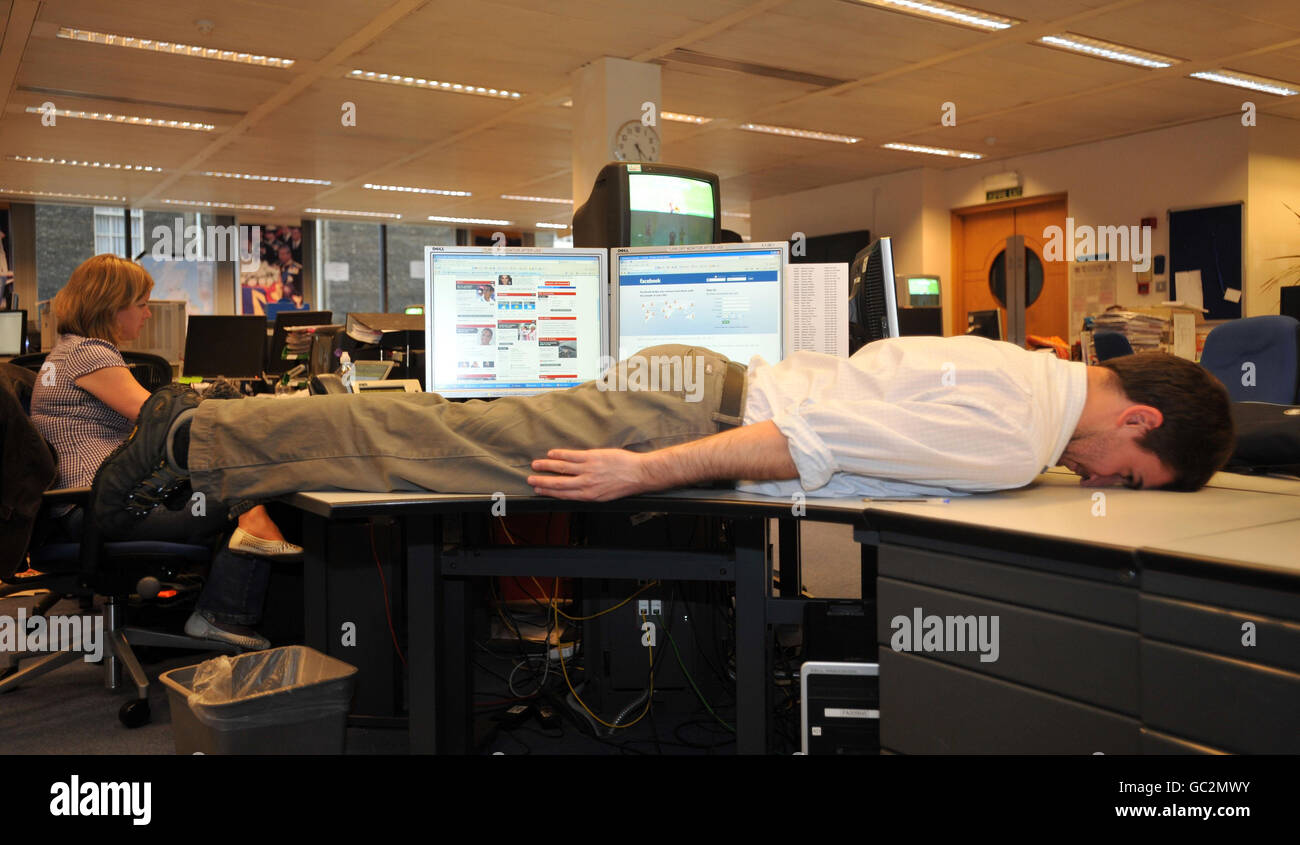 An office worker lies face down across a desk hires stock photography