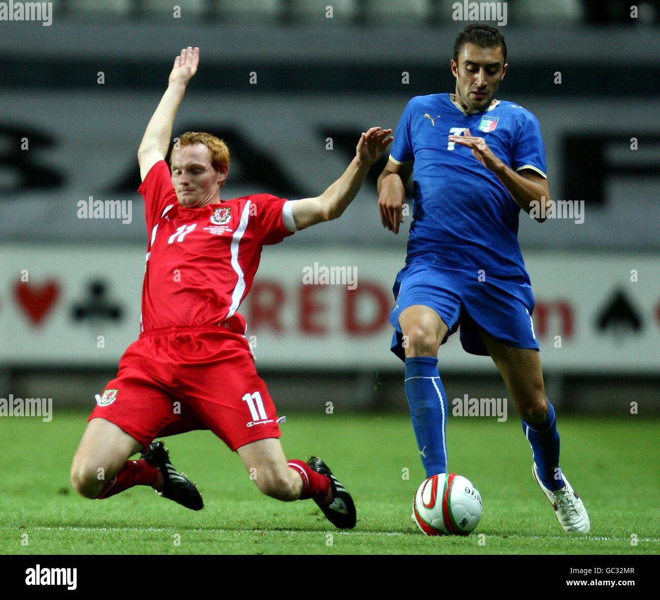Wales' Shaun MacDonald (left) goes down under the challenge of Italy's Tommaso Bianchi during the UEFA Under 21 Qualifying match at the Liberty Stadium, Swansea . Stock Photo