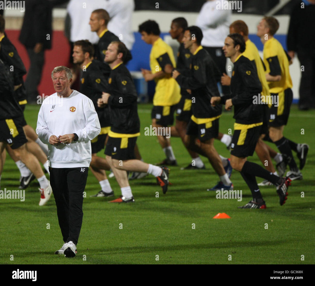 Manchester United's Manager Sir Alex Ferguson walks around pitch as players jog past him during the training session at the Inonu Stadium, Istanbul, Turkey. Stock Photo