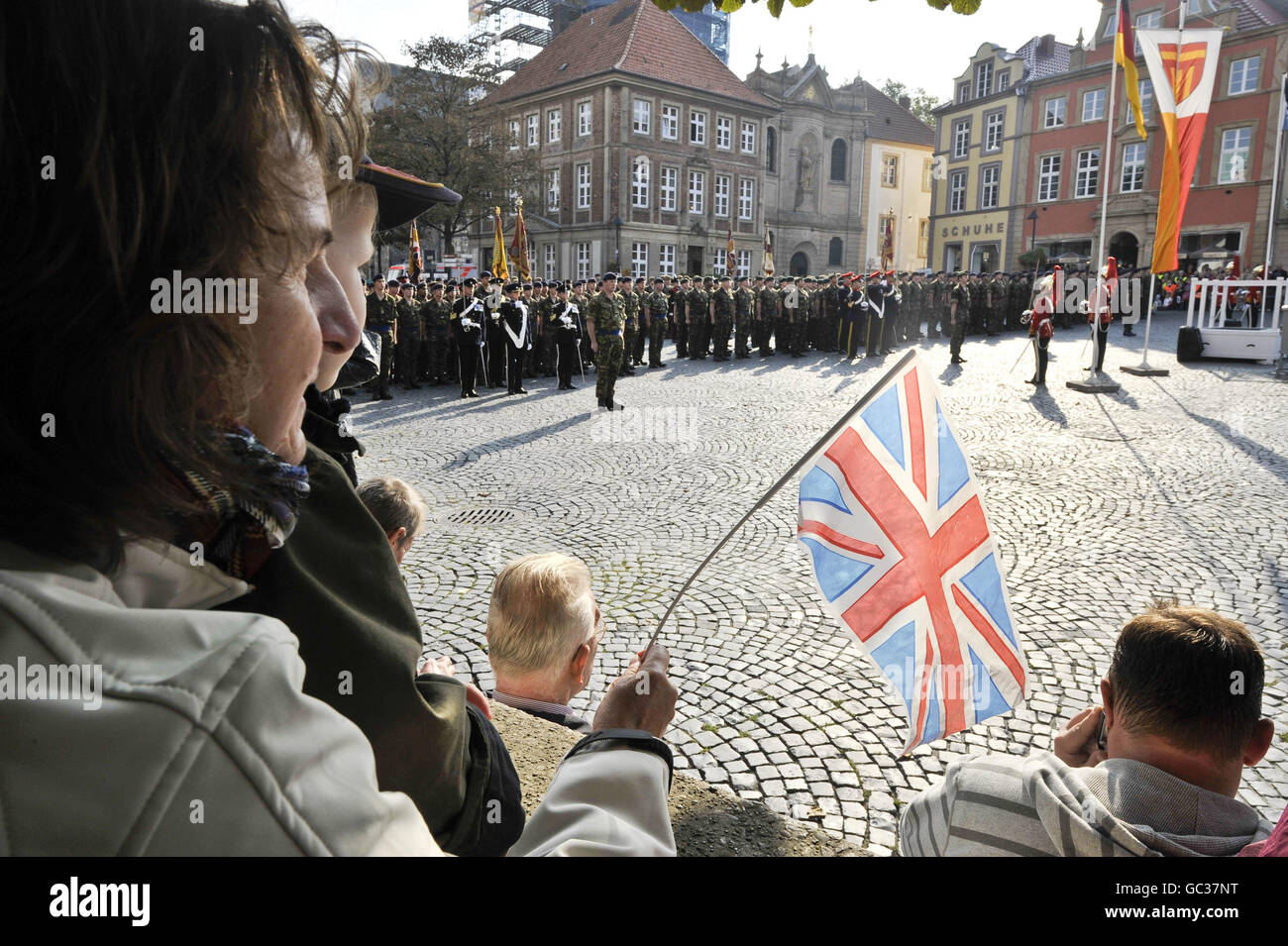 A German woman waves a Union flag as over 500 soldiers from 20th Armoured Brigade - the Iron Fist, mark their return from operations in Iraq, Afghanistan and Kosovo by parading through their Garrison town of Paderborn in front of hundreds of spectators from both the local German community and soldier's families and friends. Stock Photo