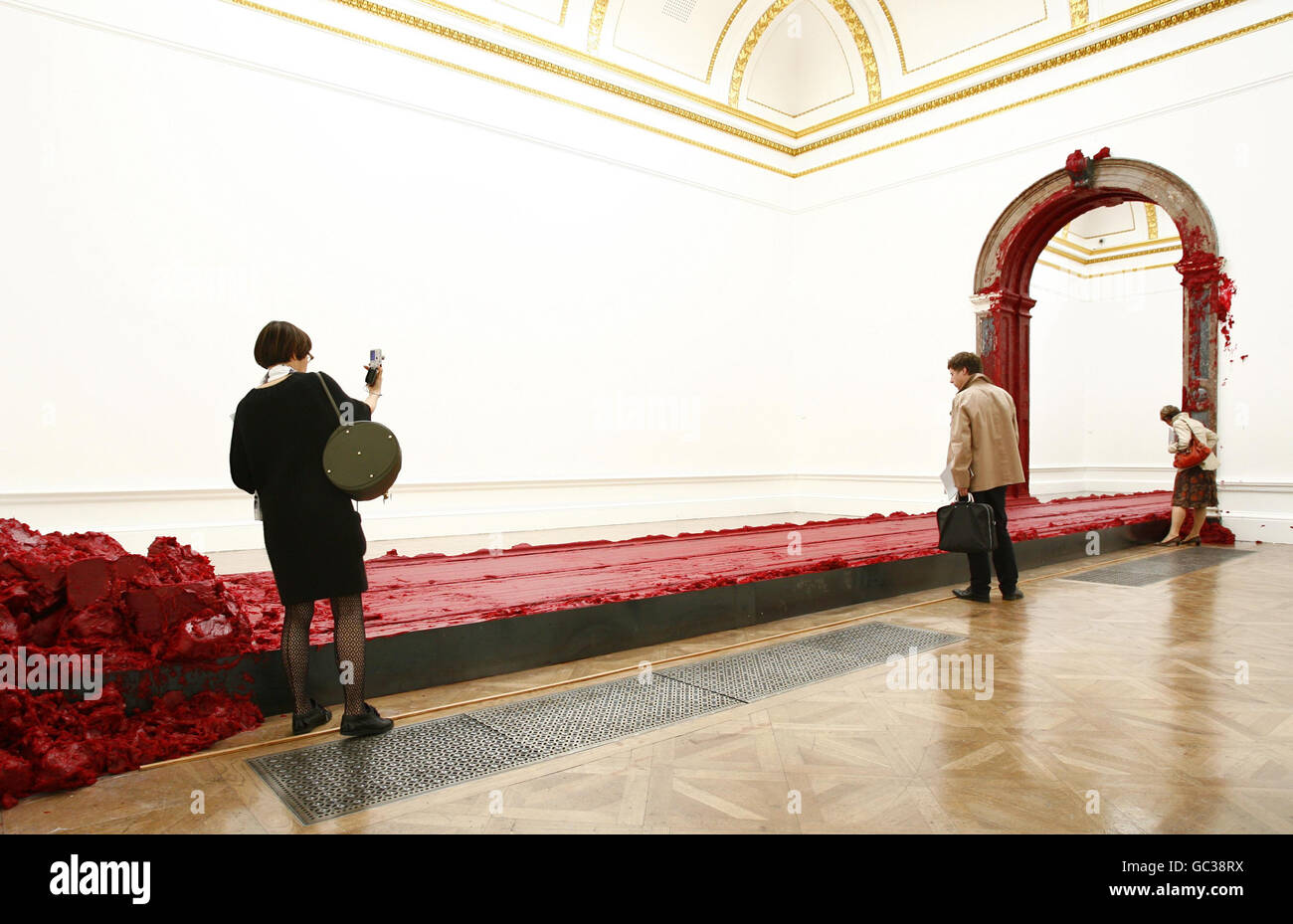 Visitors look at artist Anish Kapoor's Svayambh, 2007, during a press preview of a major solo exhibition of his work at the Royal Academy of Arts in central London. Stock Photo