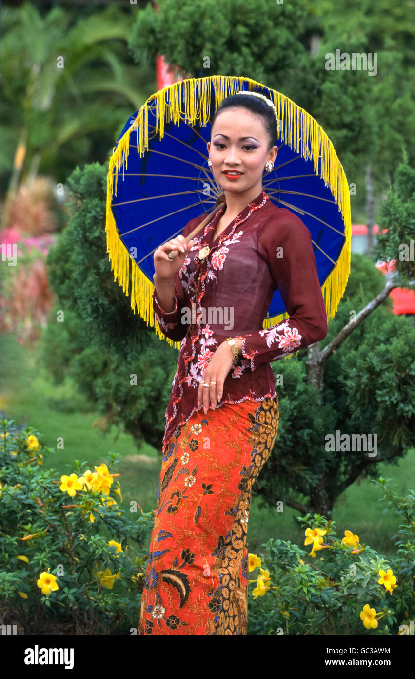 A young Malaysian woman dressed in traditional costume with colorful umbrella Stock Photo