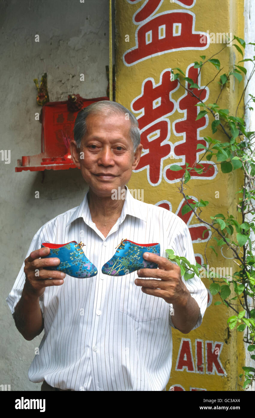 Local man holding Chinese shoes for bound feet, Melaka, Malaysia, Southeast Asia Stock Photo