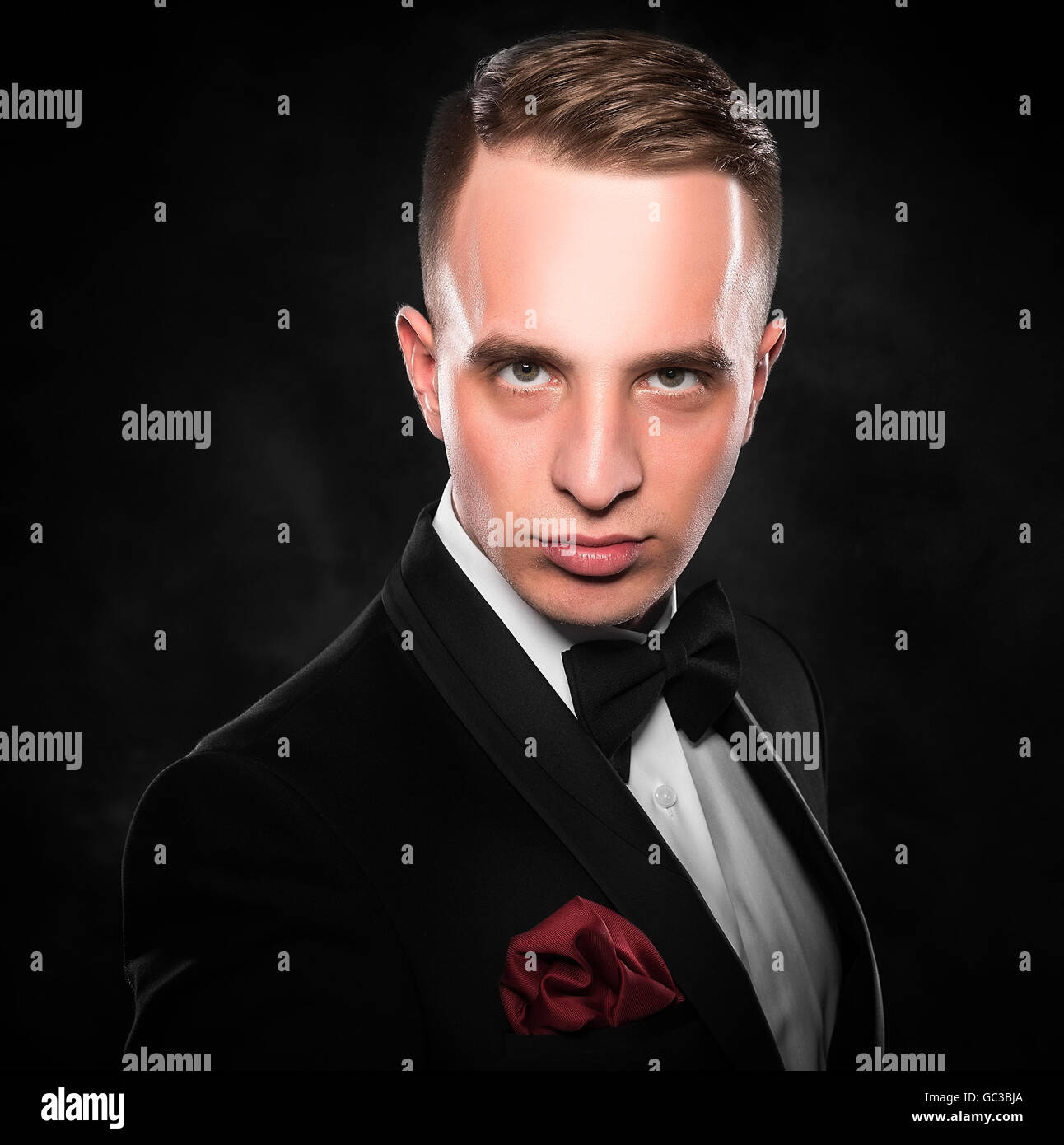 Young handsome man in black suit on dark background Stock Photo - Alamy