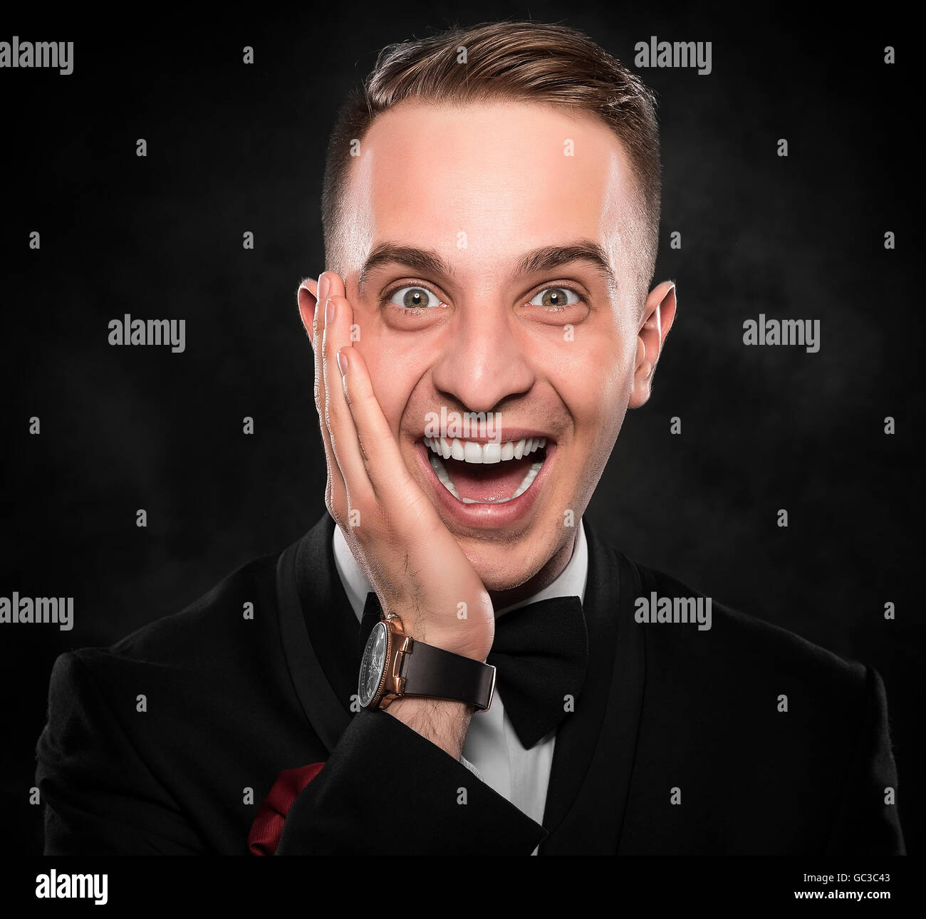 Young handsome man in black suit smiling on dark background Stock Photo ...