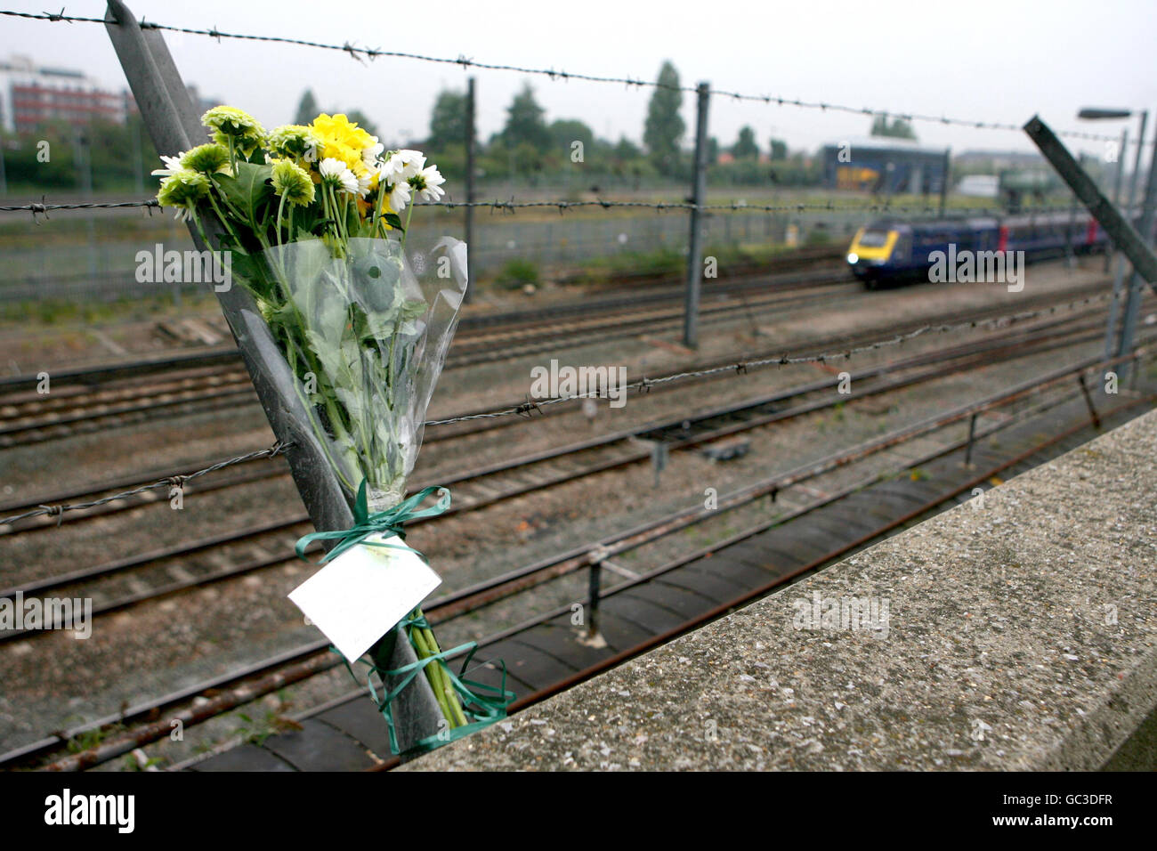 A First Great Western train approaches London as flowers are left by survivors and bereaved families who came to mark the 10th anniversary of the Paddington rail crash, at Ladbroke Grove in west London. Stock Photo