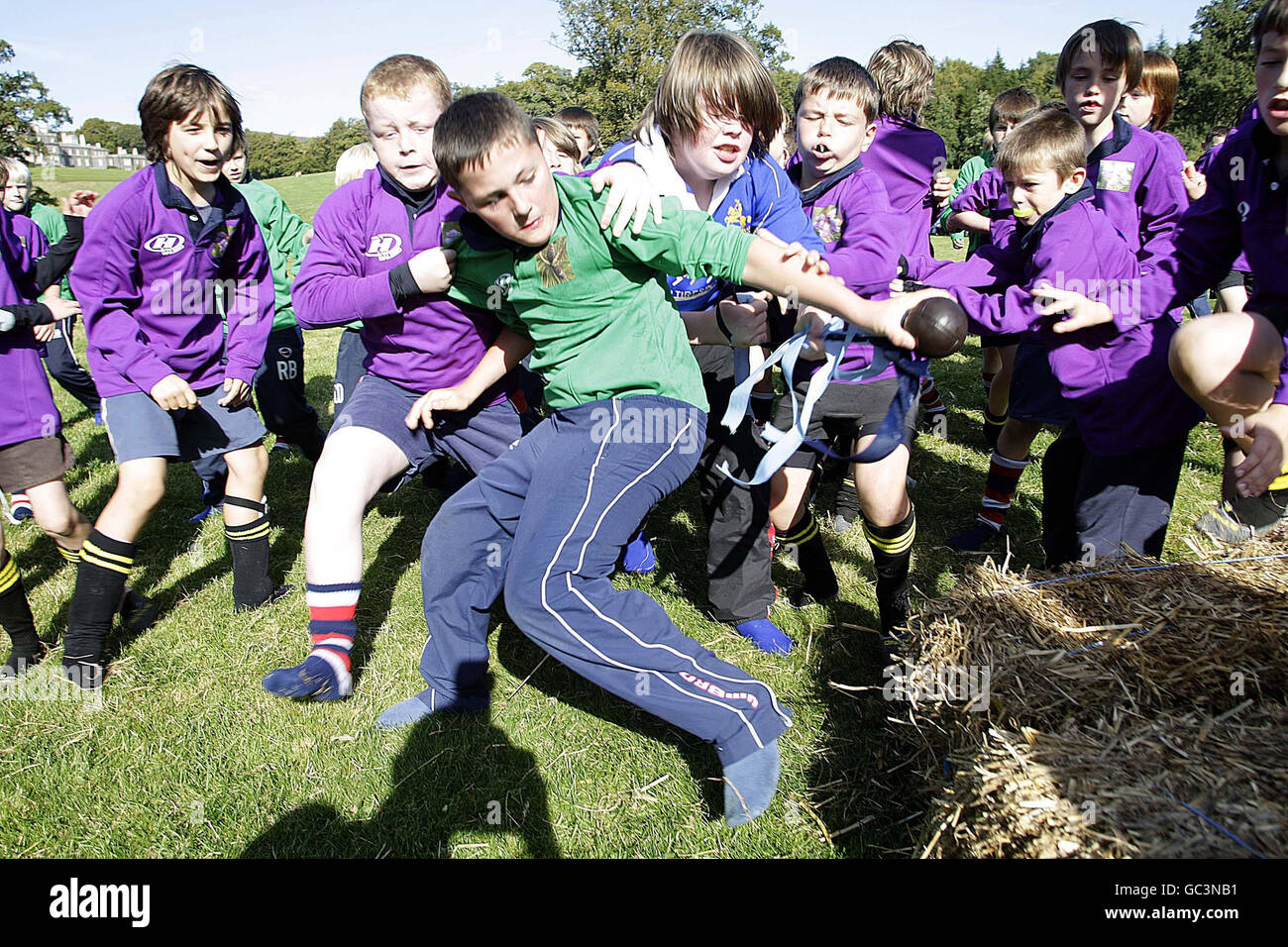 Selkirkshire's Kieran Slingsby (centre) reaches out to score a try as local school children in teams of Selkirkshire (green) and Roxburghshire (purple) take part in a re-enactment of the 1815 Carterhaugh Ba' game, that some historians believe was a forerunner to the game of rugby, at Bowhill, Selkirkshire. Stock Photo