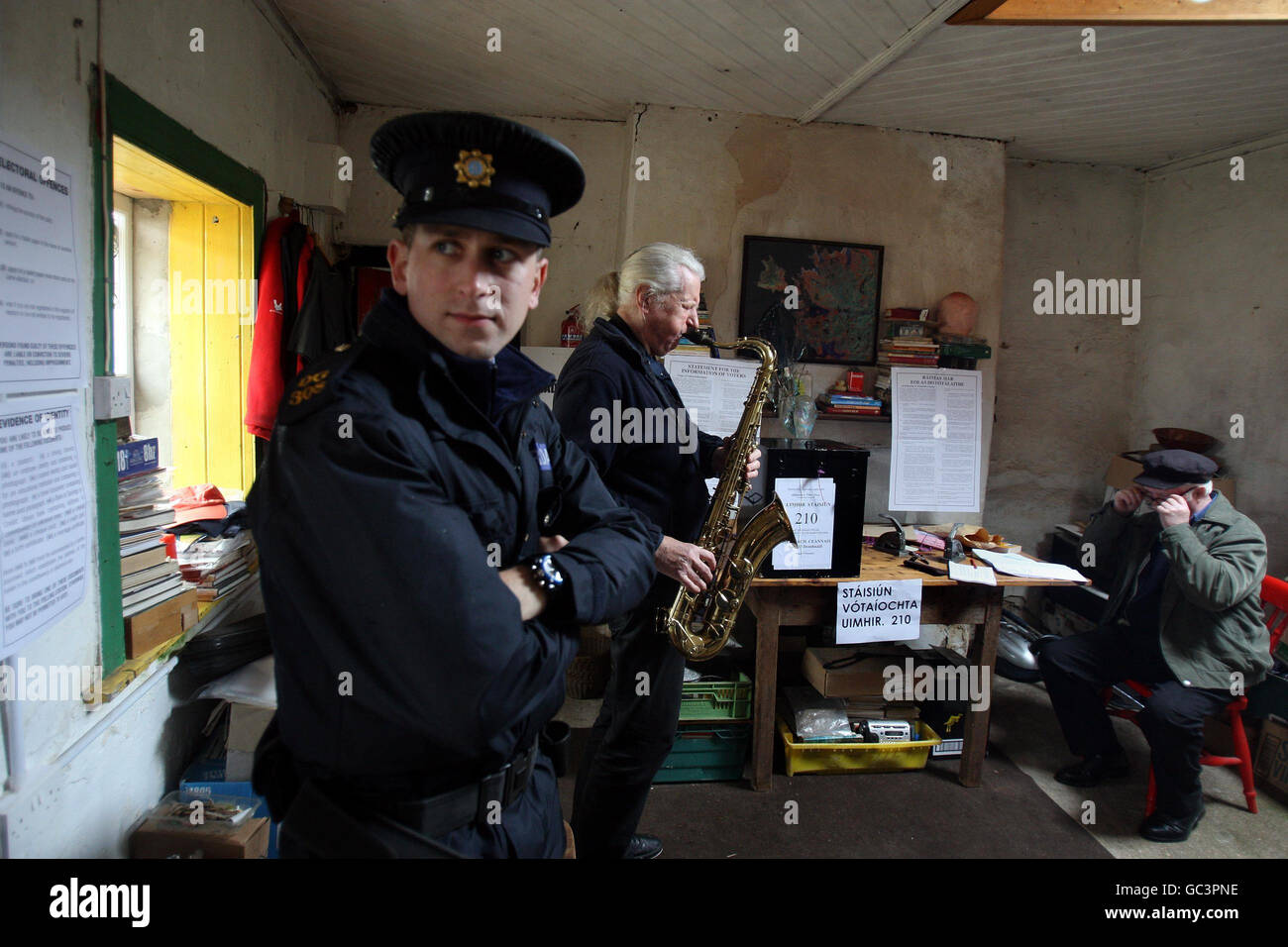 Barry Edgar Pilcher, an Inishfree islander, plays his saxophone after casting his vote on the Lisbon treaty in his living room, which has become a makeshift polling station for the islands seven inhabitants as Electoral officer, Hugh O'Donnell, right, and Garda Brendan McCann, watch on. Stock Photo