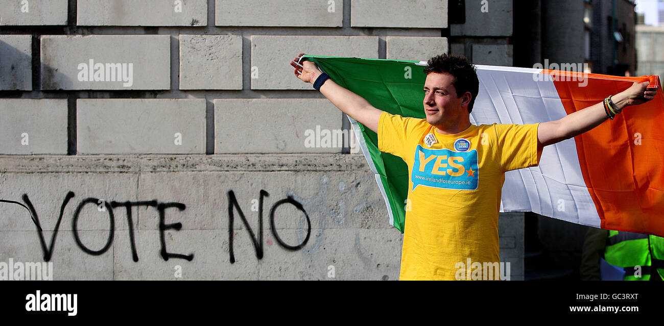 A yes supporter waves the Tricolour beside graffiti advocating a no vote at Dublin Castle, after Ireland paved the way for EU reform with more than two-thirds of voters overwhelmingly backing the Lisbon Treaty. PRESS ASSOCIATION Photo. Picture date: Saturday October 3, 2009. After the country rejected the charter last June, Irish Taoiseach Brian Cowen insisted the 67.1% 'Yes' vote in the referendum re-run was a declaration of intent to stay at the heart of Europe. See PA story IRISH Lisbon. Photo credit should read: Julien Behal/PA Wire Stock Photo