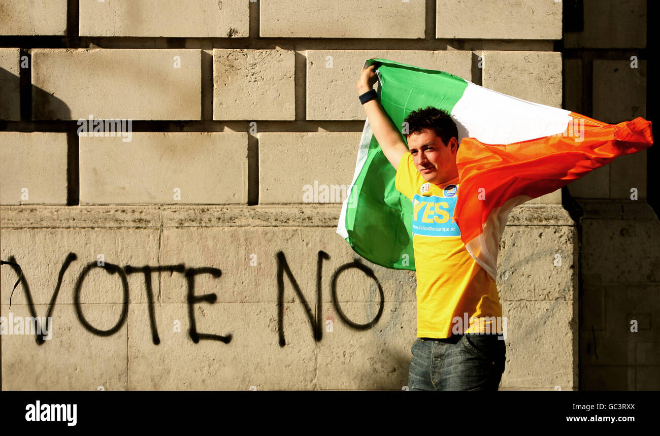 A yes supporter waves the Tricolour beside graffiti advocating a no vote at Dublin Castle, after Ireland paved the way for EU reform with more than two-thirds of voters overwhelmingly backing the Lisbon Treaty. PRESS ASSOCIATION Photo. Picture date: Saturday October 3, 2009. After the country rejected the charter last June, Irish Taoiseach Brian Cowen insisted the 67.1% 'Yes' vote in the referendum re-run was a declaration of intent to stay at the heart of Europe. See PA story IRISH Lisbon. Photo credit should read: Julien Behal/PA Wire Stock Photo