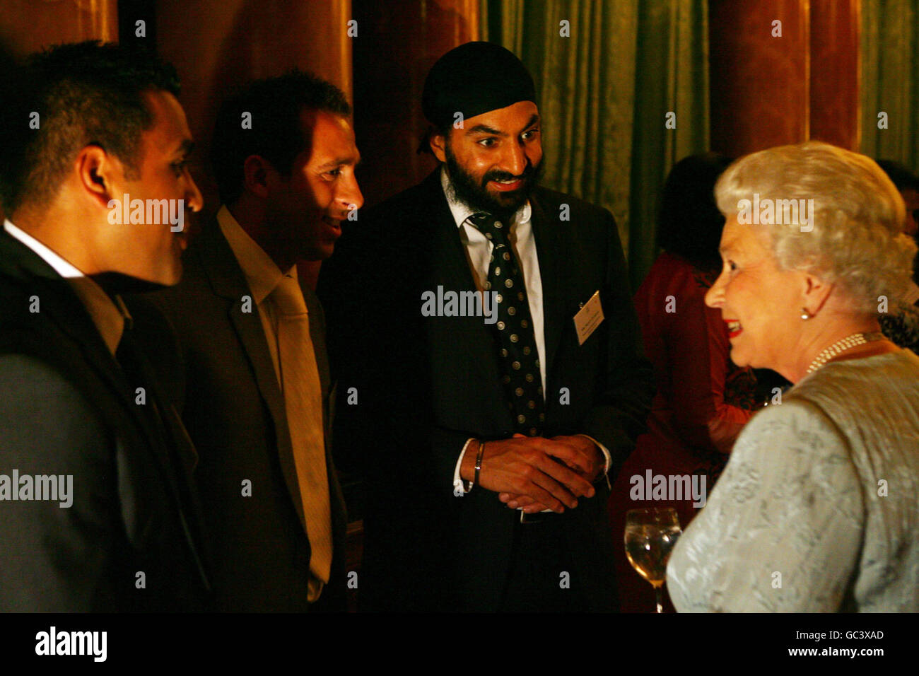 Queen Elizabeth II meets sportsmen (left to right) Samit Patel, Michael Chopra and Monty Panesar, after having watched a performance by nutkhut, a London-based British-Indian dance company, who had presented an extract of Bollywood Steps, during a reception inside the ballroom of Buckingham Palace in central London. Stock Photo