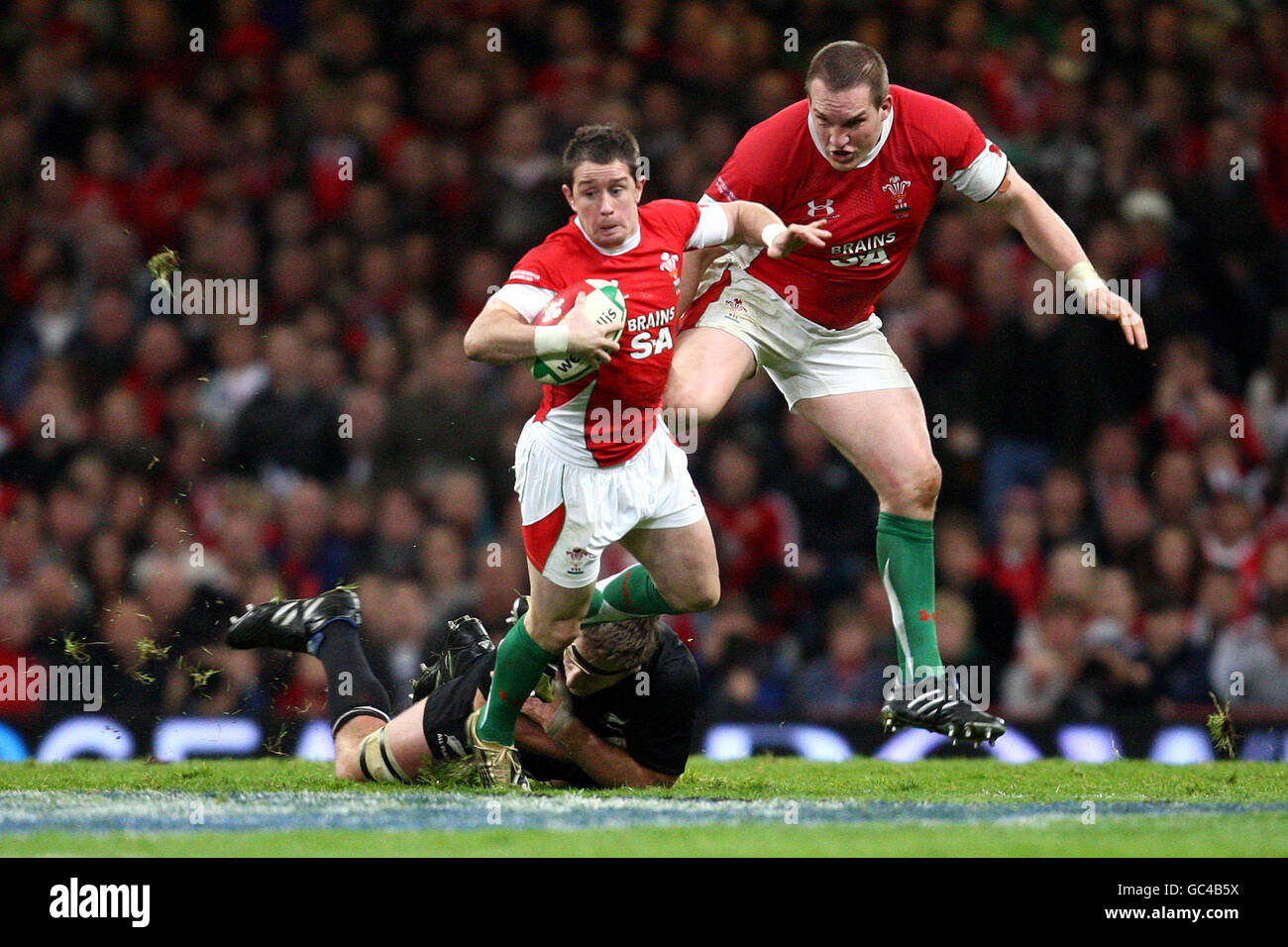 Wales' Shane Williams (centre) supported by Gethin Jenkins evades New Zealand's Brad Thorn (floor) during the Invesco Perpetual Series match at the Millennium Stadium, Cardiff. Stock Photo