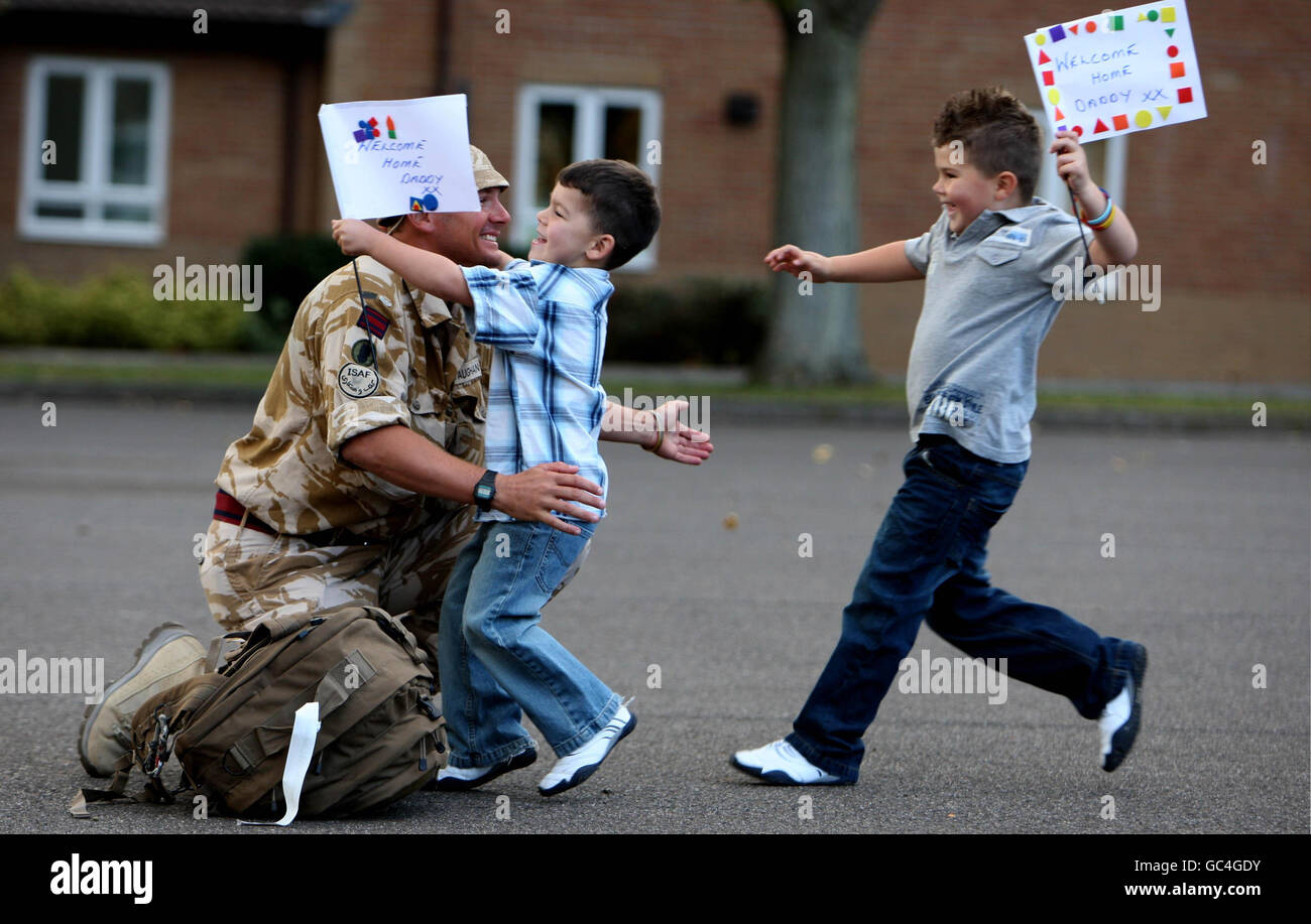 Staff Sergeant Kevin Vaughan is greeted by his sons Owen, five, left, and Bradley, 6, as 75 Royal Engineer and Royal Logistic Corps bomb disposal and search specialists return to Carver Barracks, Wimbish, Essex after six months in Afghanistan. Stock Photo