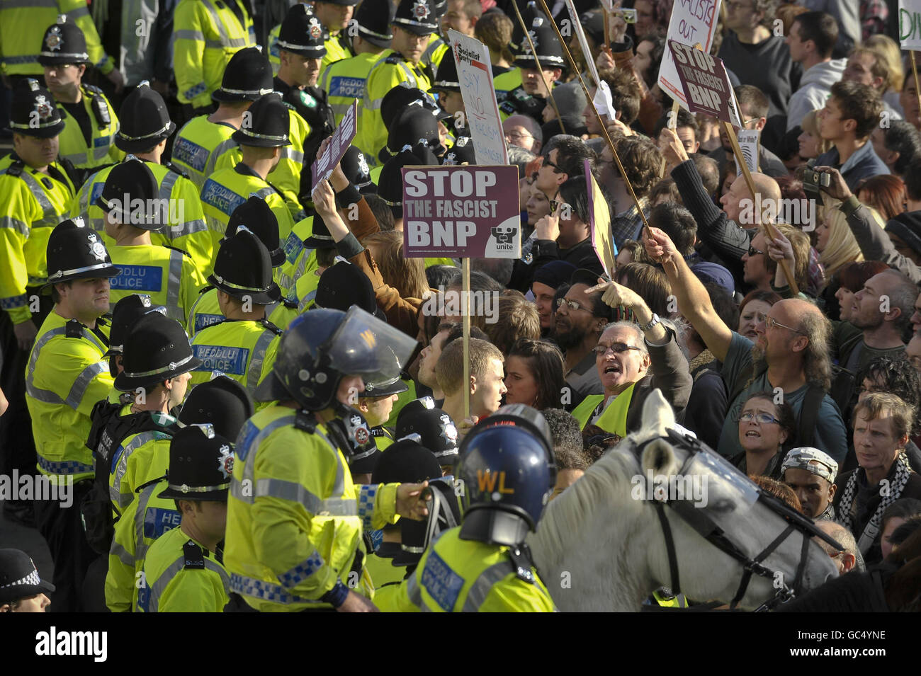 Police hold back chanting anti-fascist protesters during a protest near Castle Square, Swansea, Wales. Stock Photo