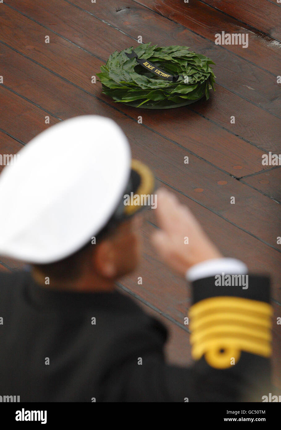 A Royal Navy captain salutes the spot on the deck of HMS Victory in ...