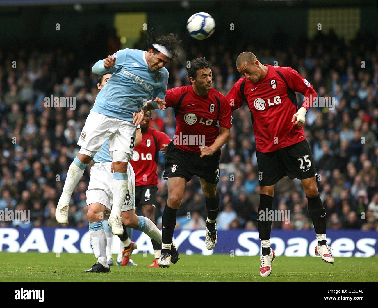 Soccer - Barclays Premier League - Manchester City v Fulham - City of Manchester Stadium. Manchester City's Carlos Tevez (left) directs a header on goal, under pressure from Fulham's Stephen Kelly (centre) and Bobby Zamora Stock Photo