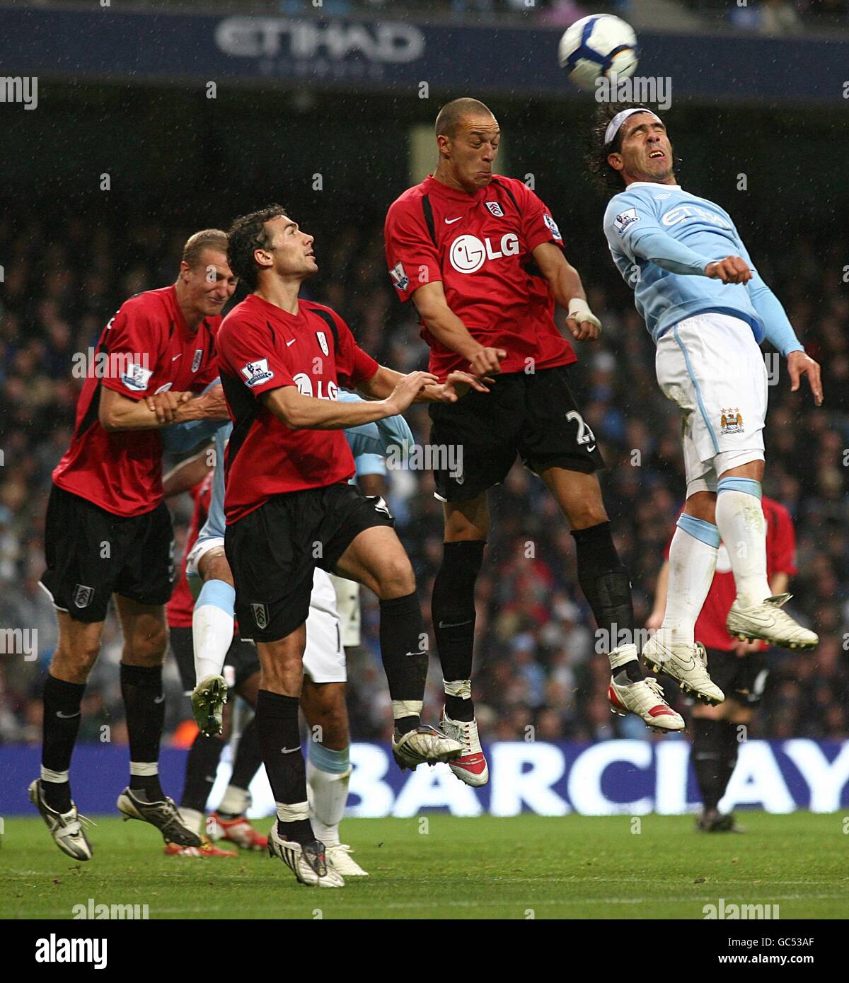 Manchester City's Carlos Tevez (right) directs a header on goal, under pressure from Fulham's Stephen Kelly (left centre) and Bobby Zamora Stock Photo