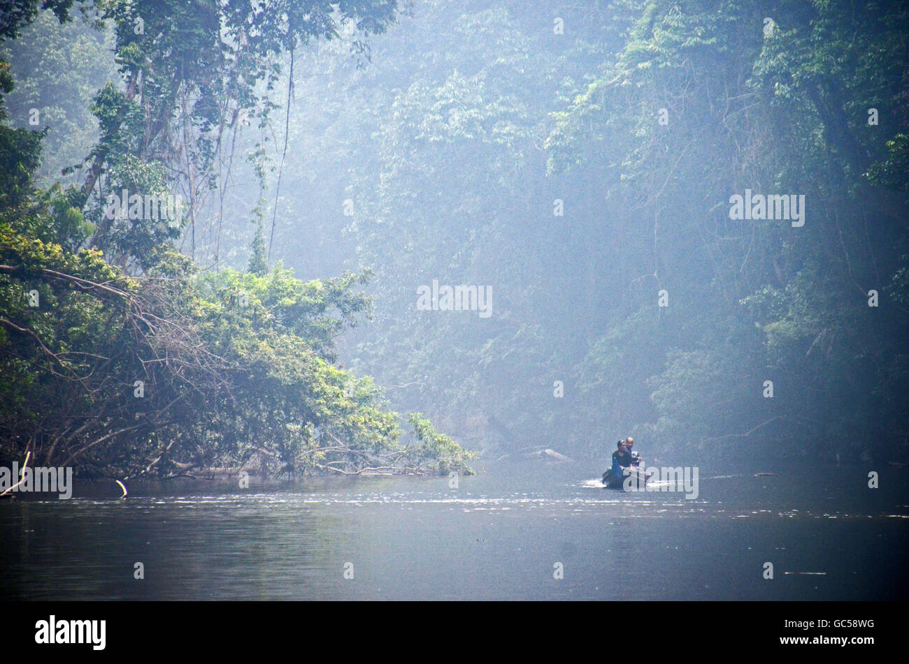 A small boat heads upstream on the Tahan River at Lubok Simpon swimming area, Taman Negara National Park, Malaysia Stock Photo