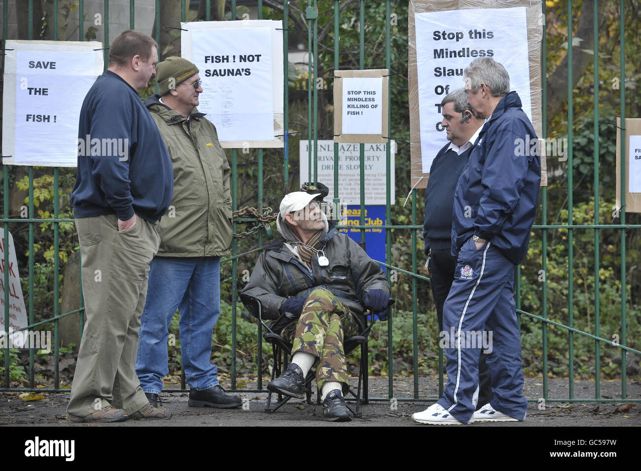 Dave Hodge (sitting centre), aged 59 from Westbury-on-Trym, is chained to the entrance gates at Henleaze swimming club, Henleaze, Bristol, where fish are scheduled to be culled to make the lake safe for swimmers. Stock Photo