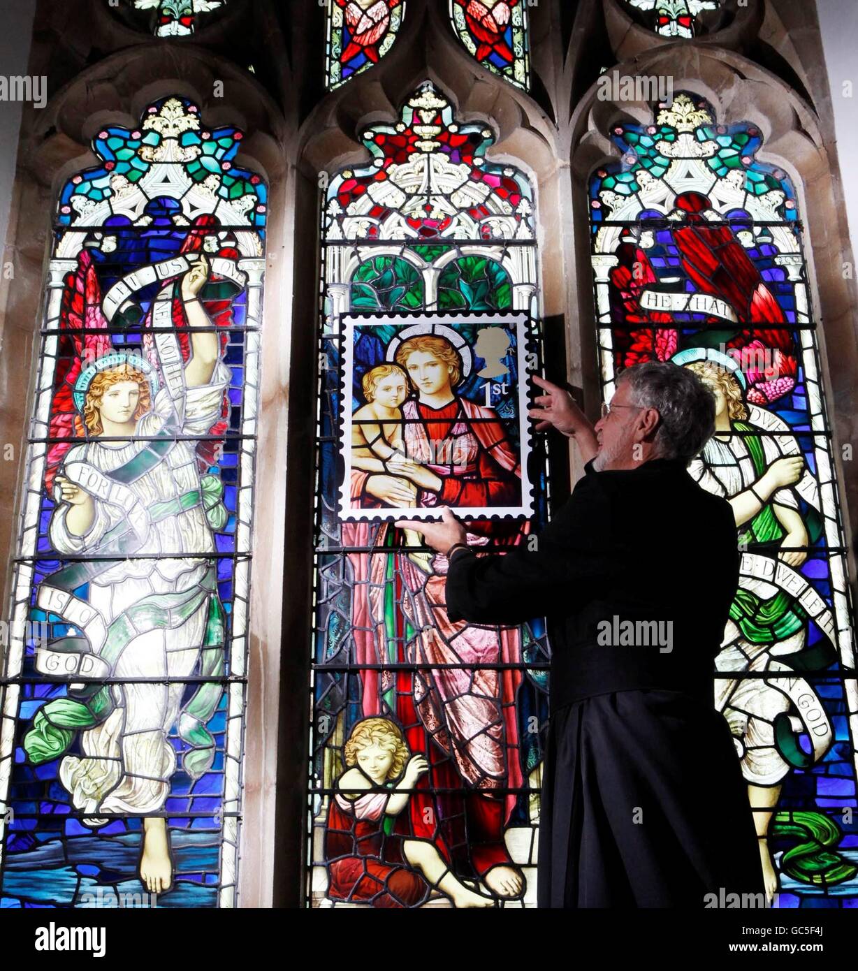 Reverend Neil Spencer holds a blown-up stamp in front of the Henry Holiday stained glass window at St Michael church in Ormesby, Norfolk, which features on a 1st class stamp from Royal Mail's Christmas stamp issue, which goes on sale today. Stock Photo