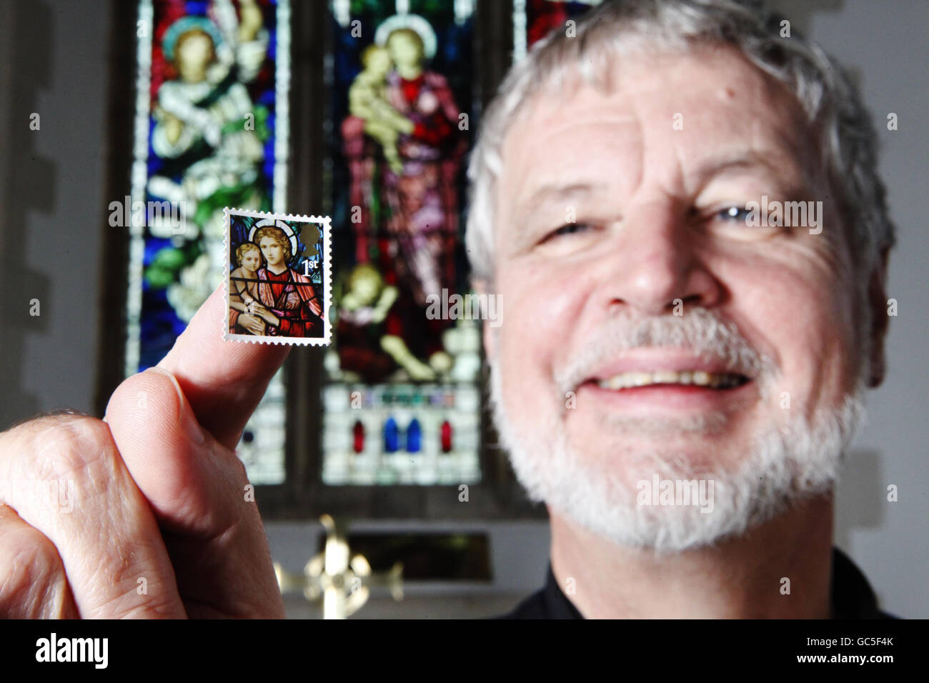 Reverend Neil Spencer holds a blown-up stamp in front of the Henry Holiday stained glass window at St Michael church in Ormesby, Norfolk, which features on a 1st class stamp from Royal Mail's Christmas stamp issue, which goes on sale today. Stock Photo