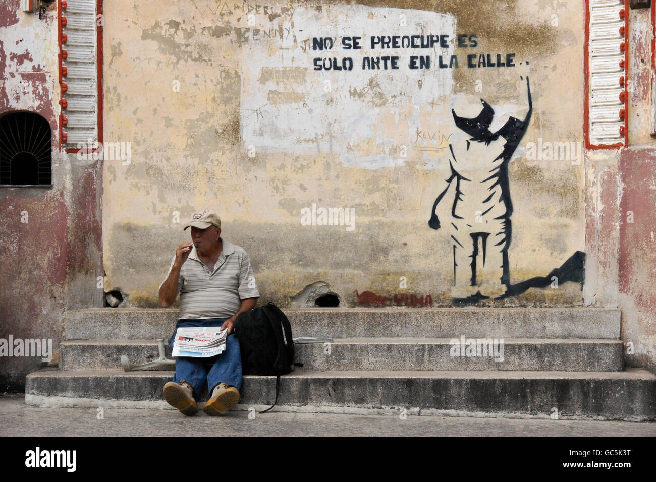 Man reading newspaper on steps of Teatro Cespedes, Regla, Cuba Stock Photo