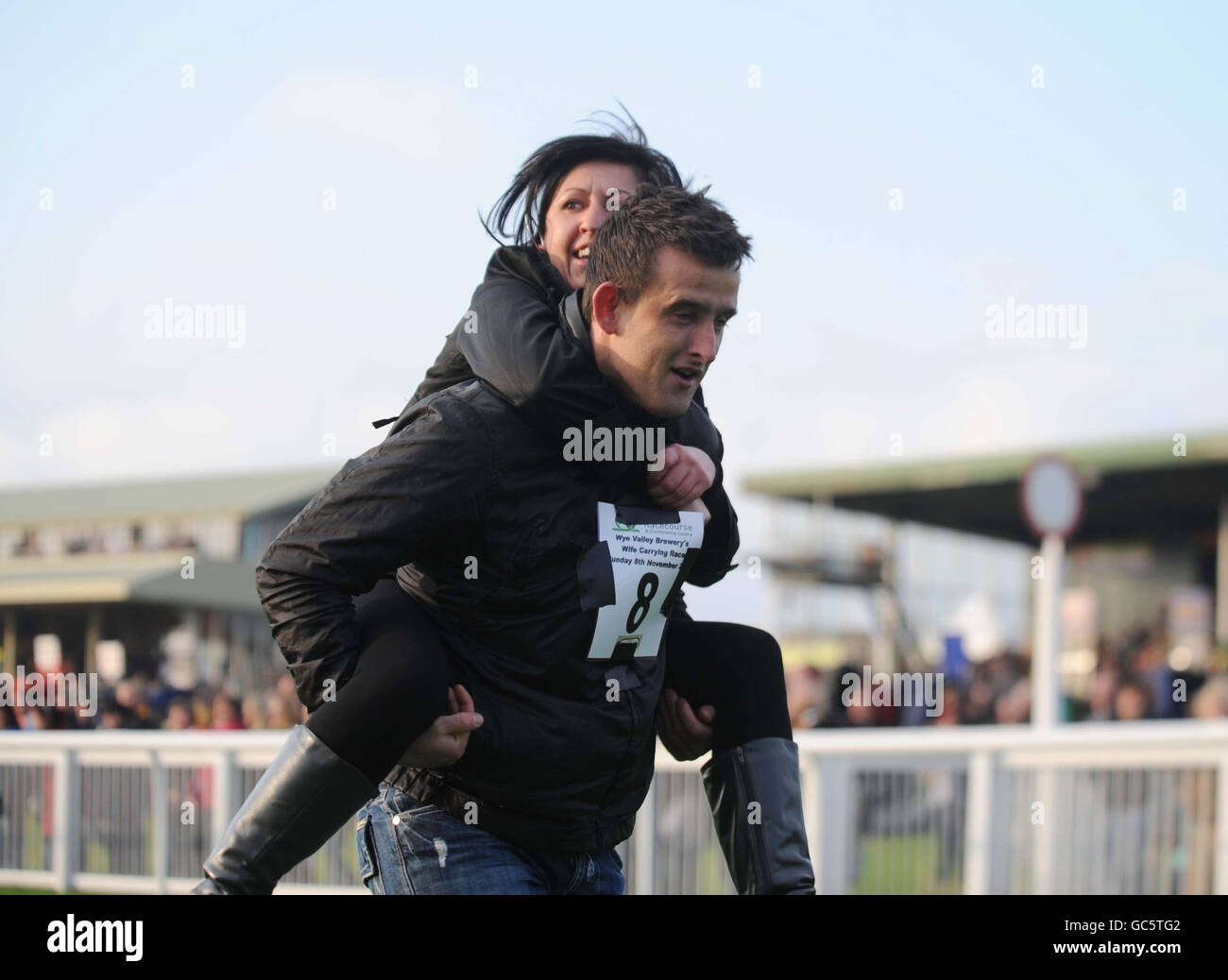 The winning couple of the wife carrying race Oliver Milligan and girlfriend Christina Davies both from Ebbw Vale at Hereford Racecourse crossing the finishing line. The race was sponsored by Wye Valley Brewery and the prize is their combined body weight in beer. Stock Photo