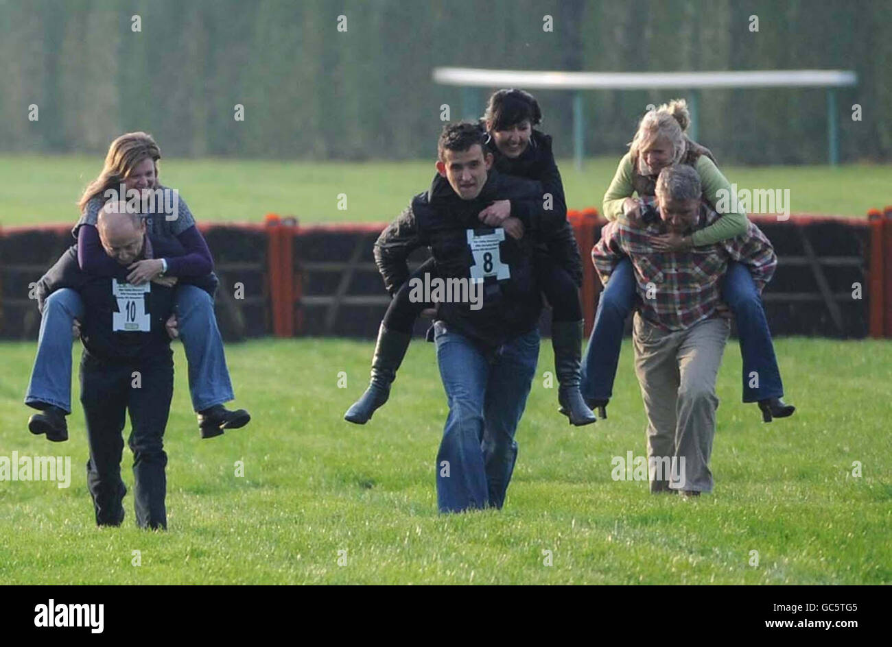 Wife carrying race with the winners Oliver Milligan carrying girlfriend Christina Davies (centre) both from Ebbw Vale at Hereford Racecourse. The race was sponsored by Wye Valley Brewery and the prize is their combined body weight in beer. Stock Photo