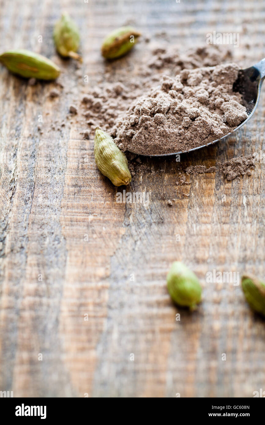 Scattered pods and spoon of powdered cardamom. Stock Photo