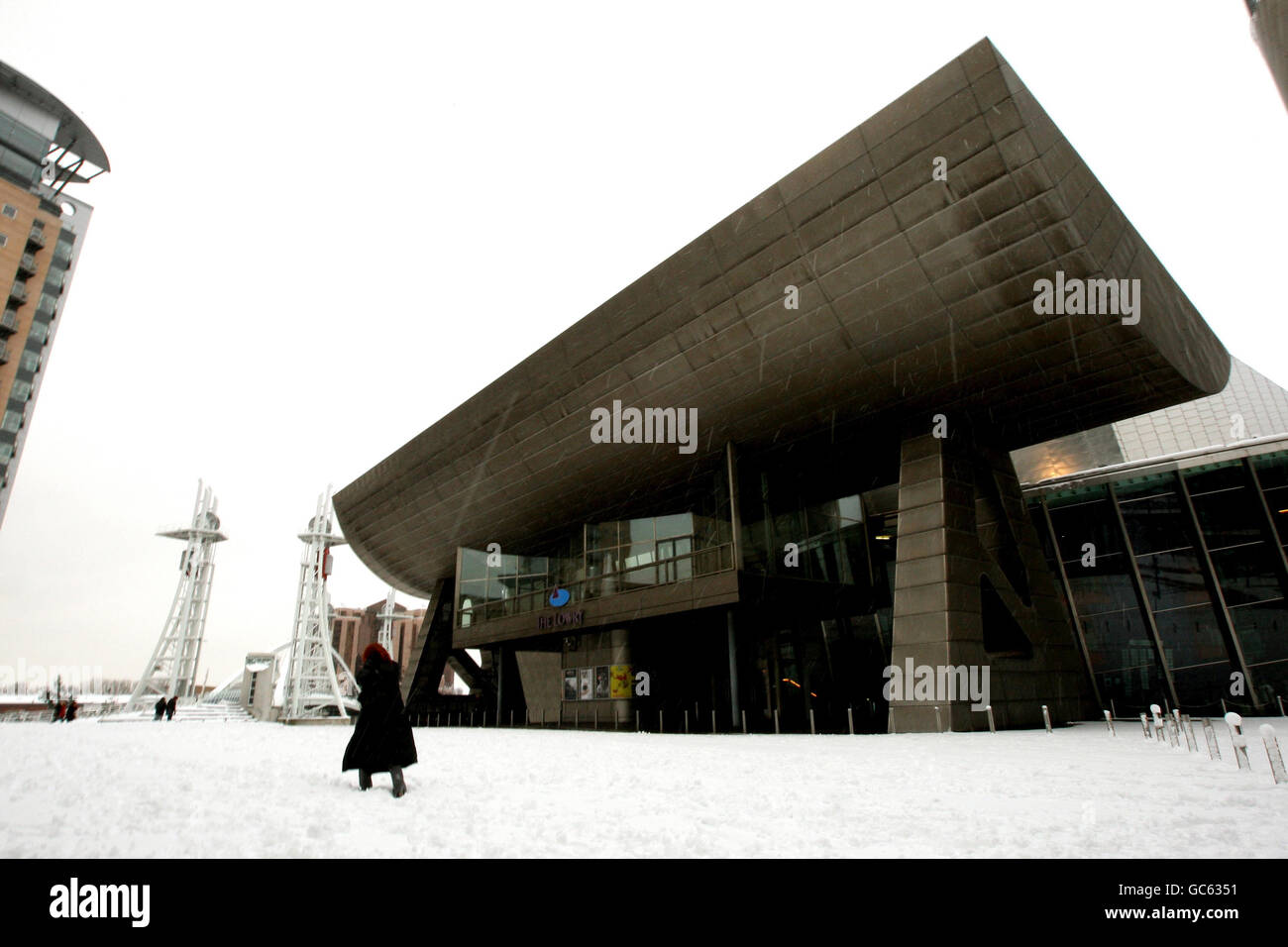 A woman walks through the snow past The Lowry in Salford Quays, Manchester, as Britain was in the grip of snow chaos. Stock Photo