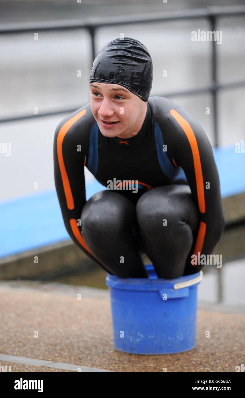 Triathlon world champion Great Britain's Alistair Brownlee warms his feet during the photocall at Serpentine Lake, London. Stock Photo