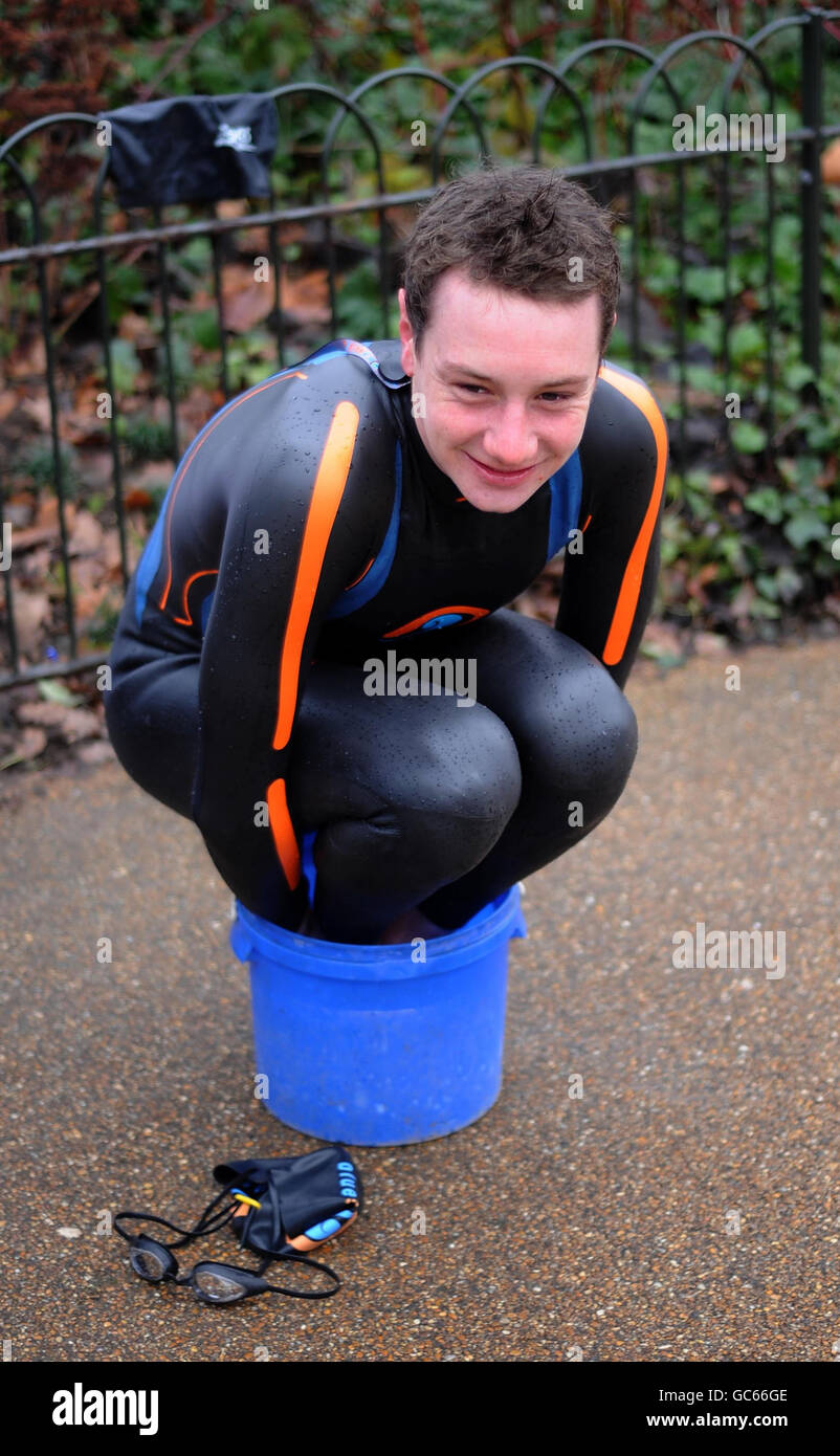 Triathlon world champion Great Britain's Alistair Brownlee warms his hands and feet during the photocall at Serpentine Lake, London. Stock Photo