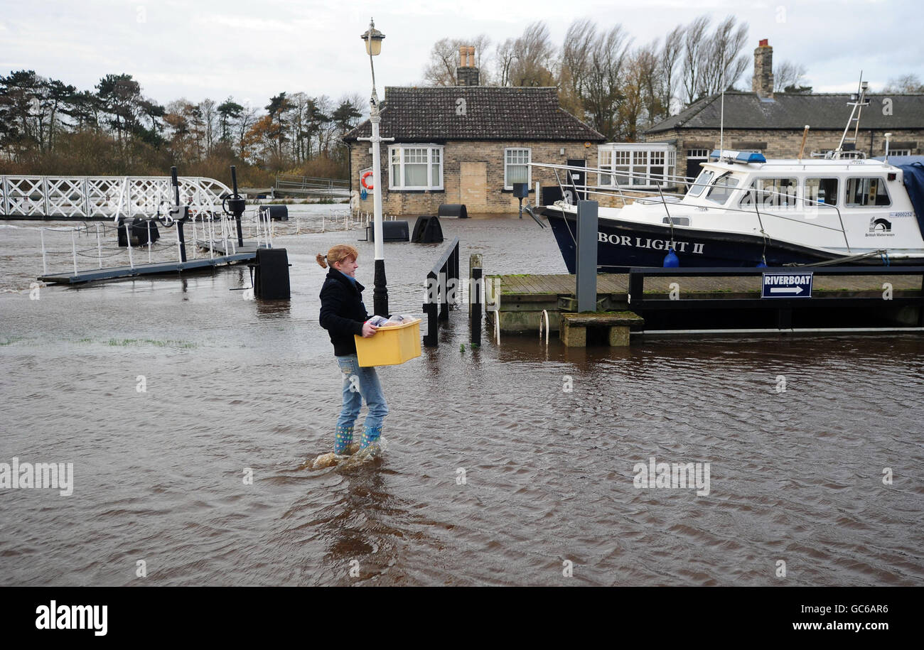 Amy Gaskell carries her shopping home through rising flood waters from the River Ouse at Naburn, York, as forecasters warn that the downpour is set to continue in northern England, north-west Wales and western Scotland. Stock Photo