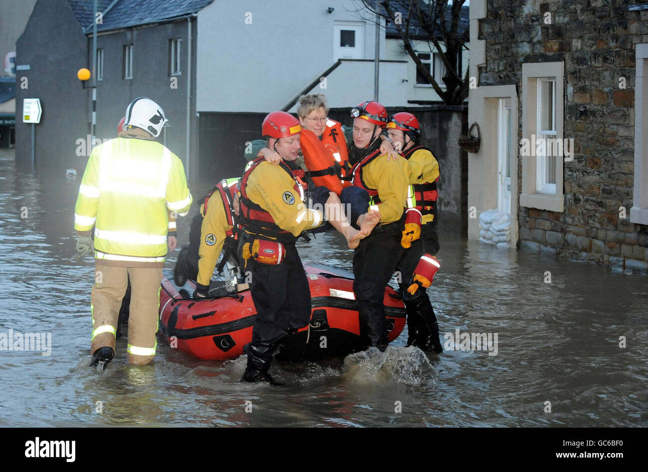 A woman is taken to safety in a dingy in Cockermouth in Cumbria after torrential rain caused rivers to burst their banks. Stock Photo