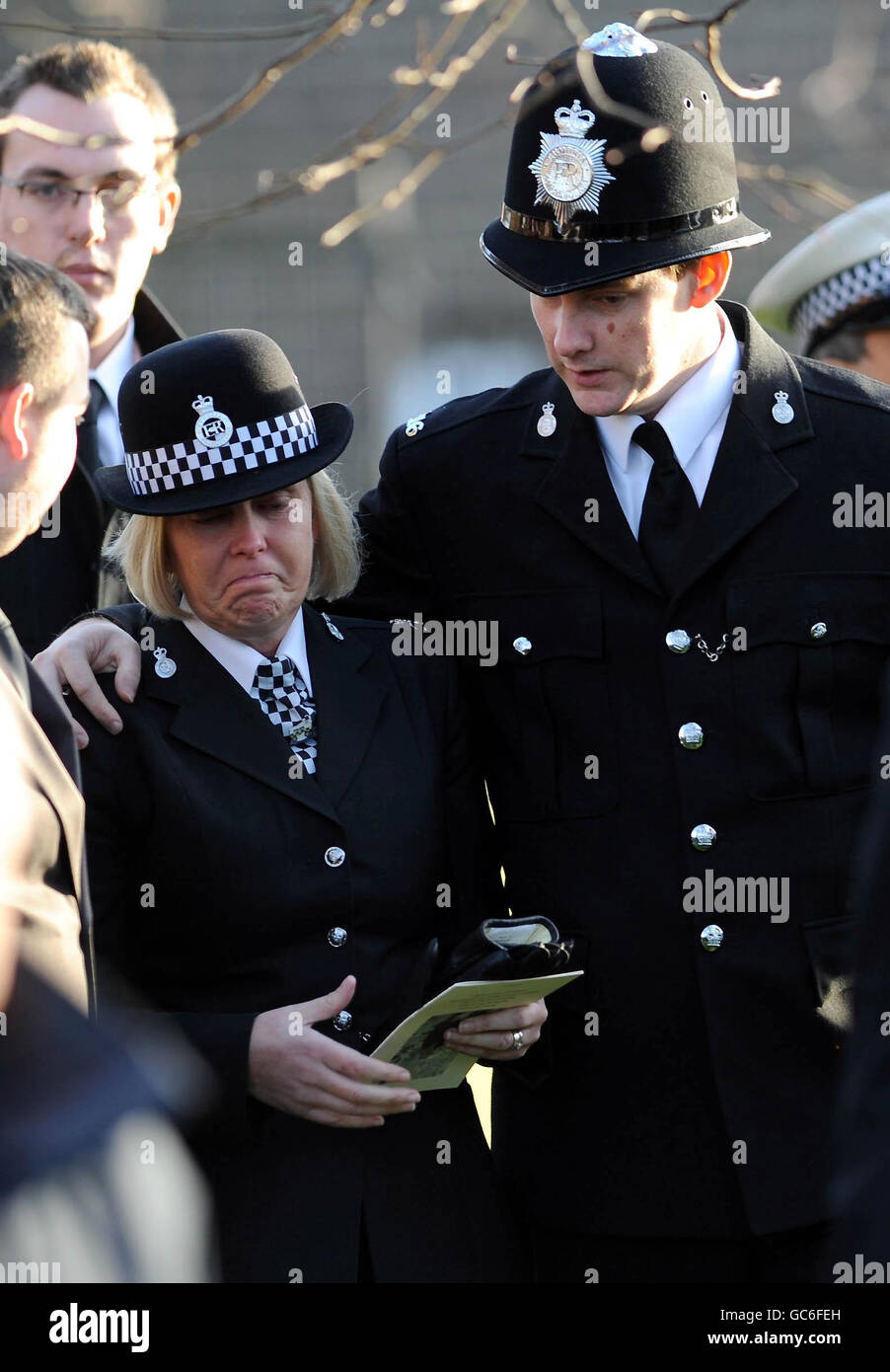 A police officer comforts a colleague at the funeral service of Pc Bill