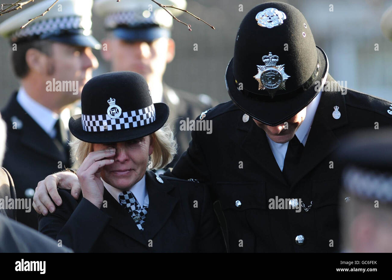 A police officer comforts a colleague at the funeral service of Pc Bill