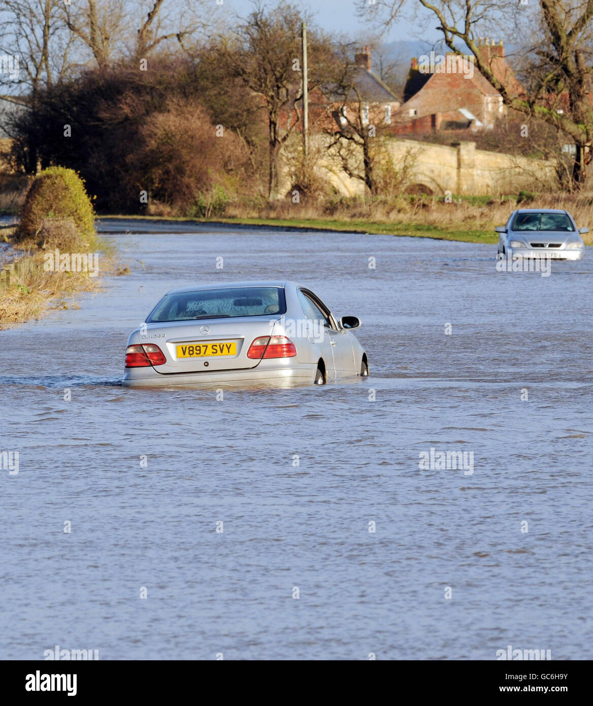 Floodwaters still affecting many parts of the UK today as rising river levels in North Yorkshire near Northallerton leave abandoned vehicles marooned on the road. Stock Photo