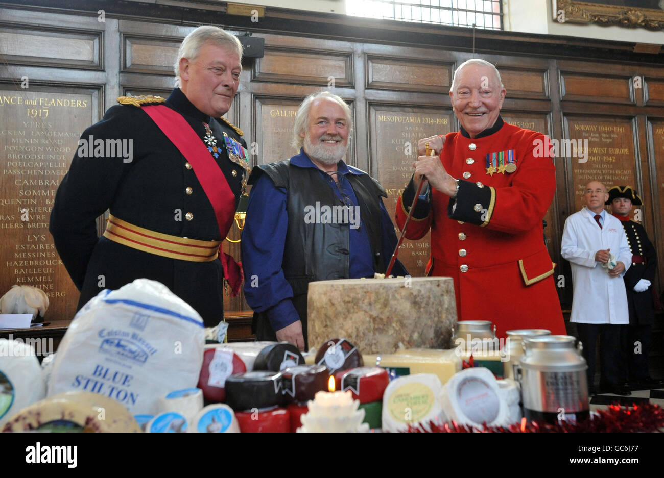 Chelsea pensioner Bill Moylon, aged 94, (right) a former prisoner of war who helped build the bridge on the River Kwai, cuts the cheese at a special Christmas ceremony at the Royal Hospital Chelsea, watched by RHC Governor, Gen Lord Walker, left, and Sandy Wilkie, Chairman of the Dairy Council. Stock Photo