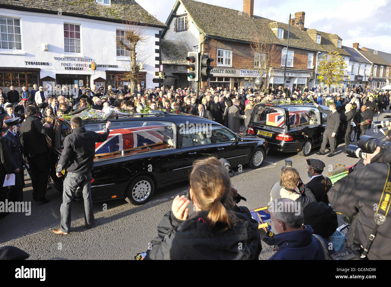 Mourners throw flowers onto the hearses at a repatriation through the Wiltshire town of Wootton Bassett as the bodies of Rifleman Philip Allen, 20, of 2nd Battalion The Rifles and Samuel John Bassett, 20, of 4th Battalion The Rifles pass through the High Street. Stock Photo