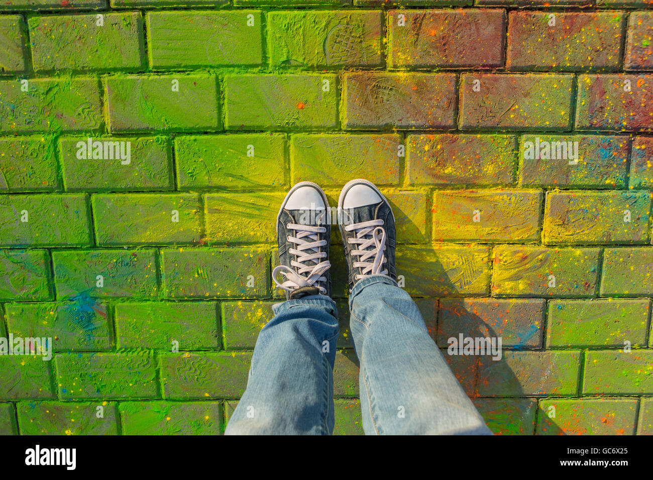 Feet in jeans sneaker on colorful Holi powder background, top view ...