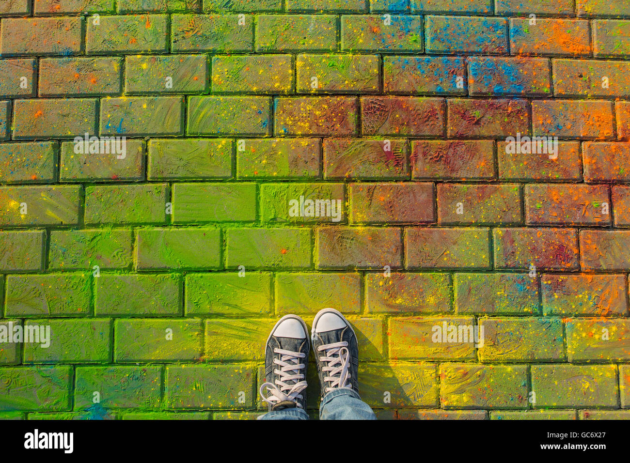 Feet in jeans sneaker on colorful Holi powder background, top view ...