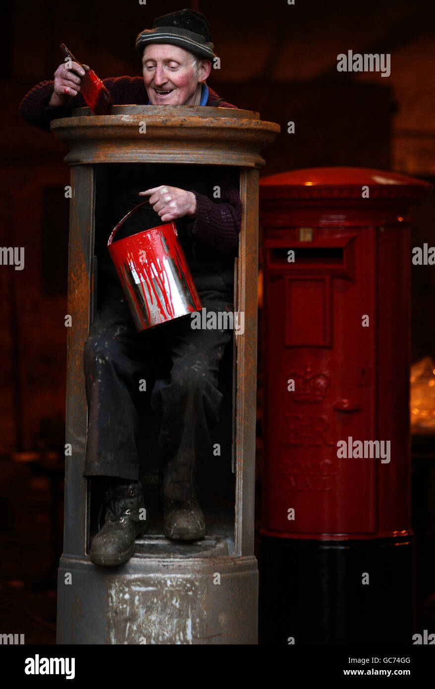 John Cooper, 69, who has been making post boxes since he was 15 years old, starts to paint a Royal Mail pillar box at Machan Engineering in Denny. Machans are the only company in the UK to manufacture the post box for the Royal Mail. Stock Photo