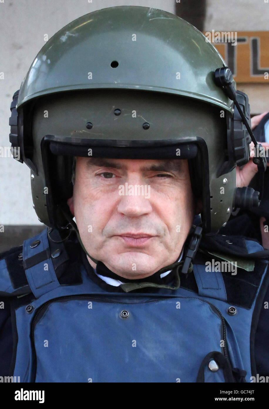 Prime Minister Gordon Brown wears a helmet and body armour as he leaves