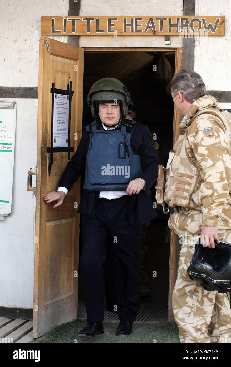 Prime Minister Gordon Brown wears a helmet and body armour as he leaves