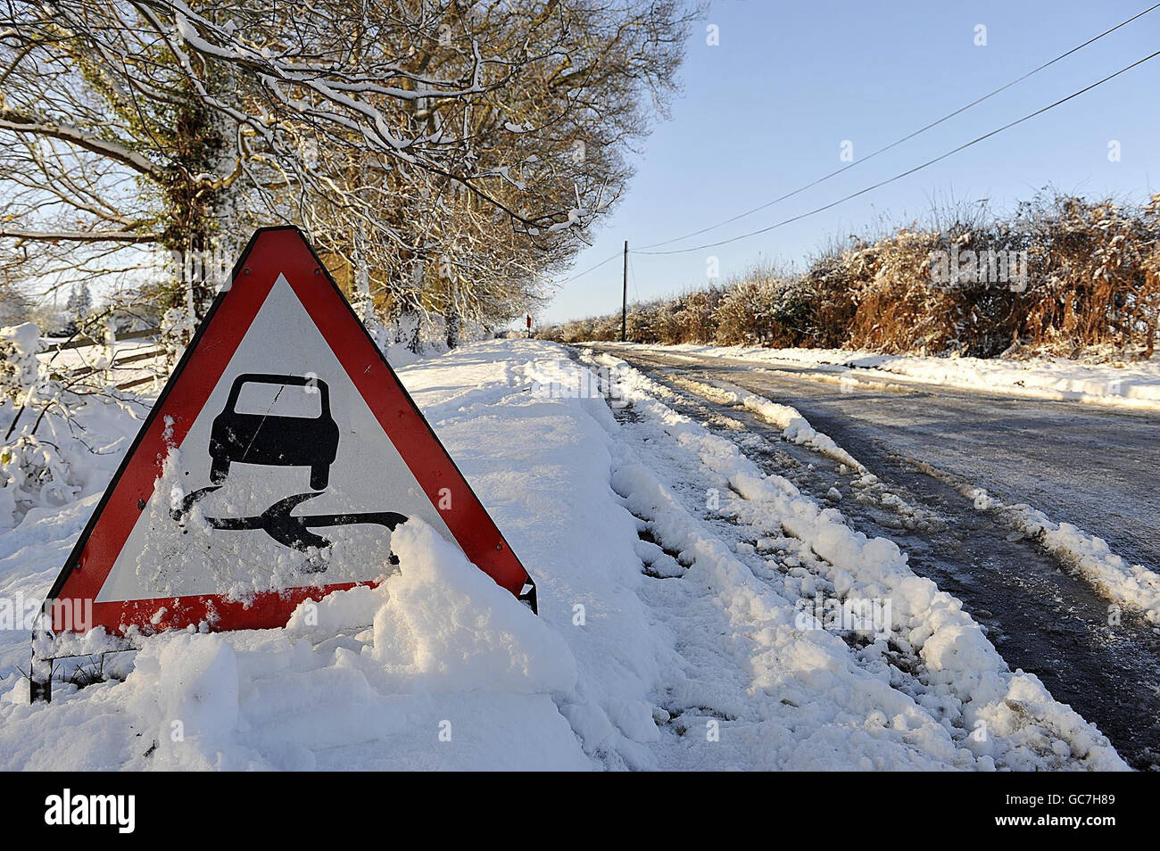 A road sign reminds drivers to take care on an ice covered road in ...