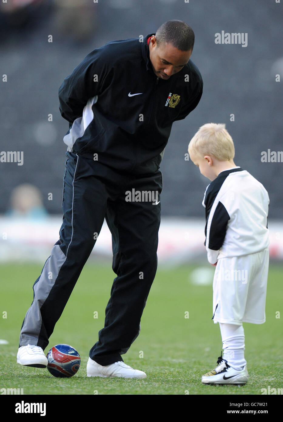 Milton Keynes Dons manager Paul Ince (left) plays football with a youngster Stock Photo