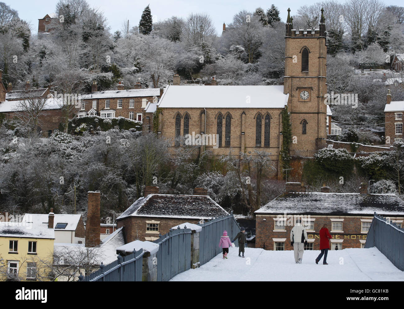 People walk in the snow over The Iron-Bridge in Ironbridge, Shropshire as heavy snowfall continues across most parts of the UK. Stock Photo