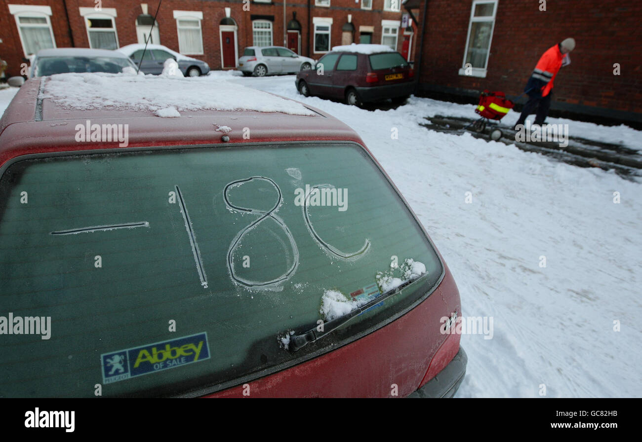 A postman delivers his mail as the overnight temperature is written in ice on a car in Stockport as the arctic conditions continue to hit the north of England. Stock Photo